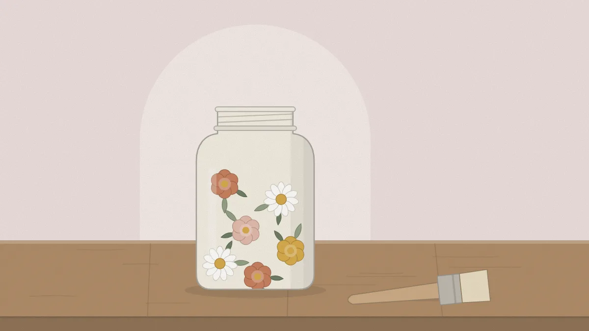 A jar covered with a floral paper napkin design on a pale painted base, with a soft brush beside it