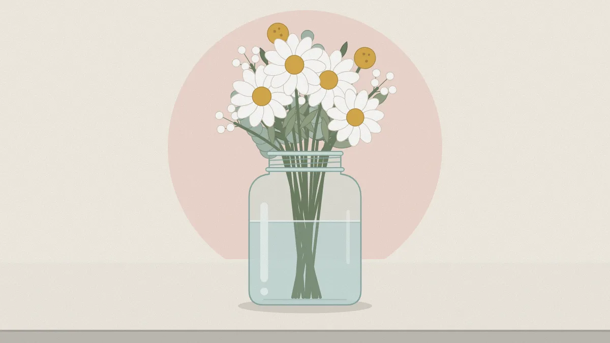 A clear quart mason jar holding a loose arrangement of daisies, small filler flowers and greenery