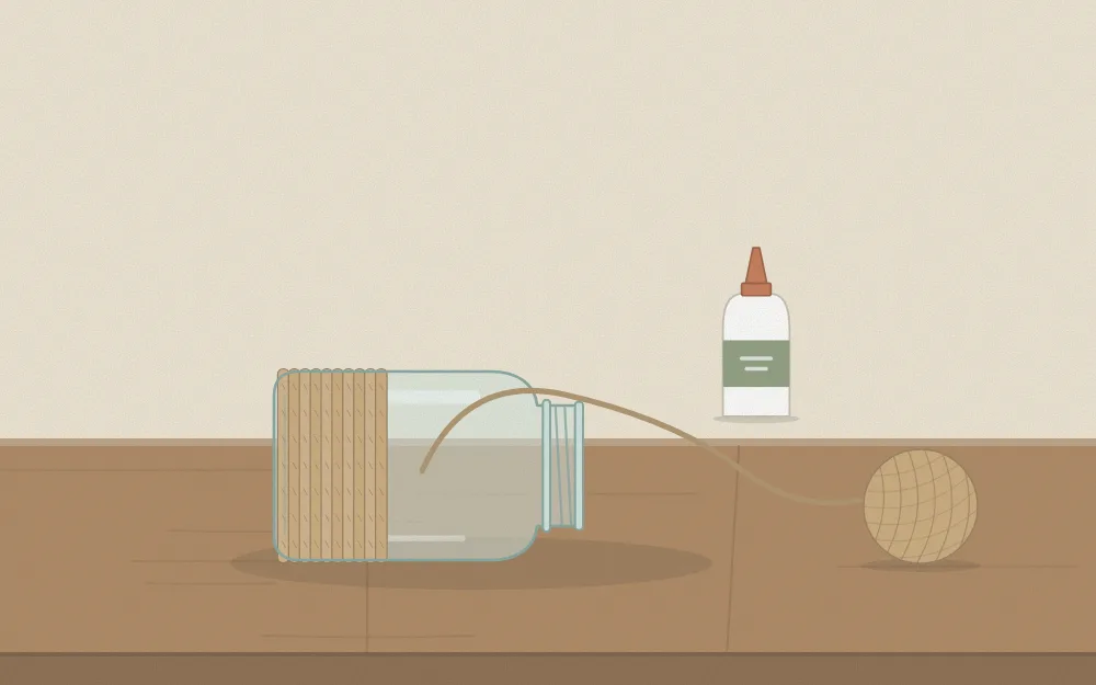 A jar lying on its side with twine wound around the lower half and a glue bottle beside it